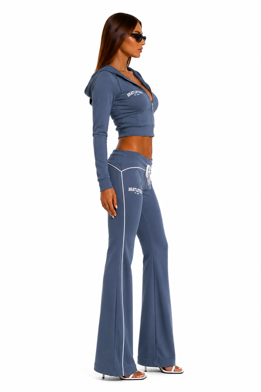 Woman wearing a blue tracksuit with 'BRATLETICS' branding on a white background