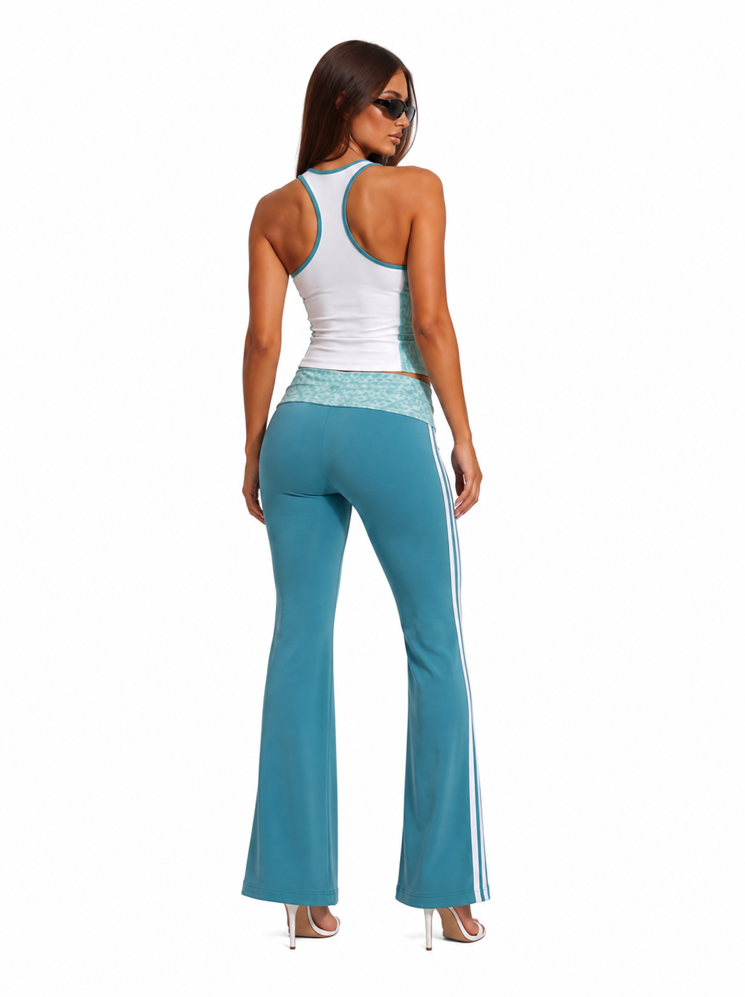 Woman wearing a white tank top and teal flared pants on a white background