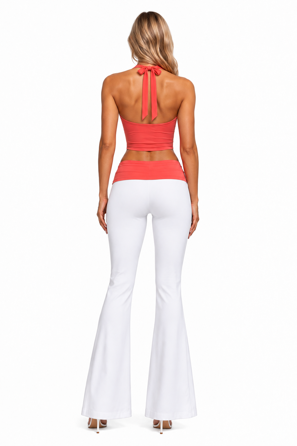 A woman shown from the back wearing a coral halter crop top with a tie-back and white flared pants, photographed against a plain white studio background.